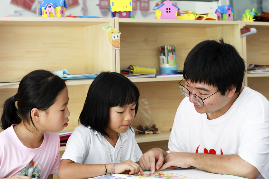 7月28日,來自南昌大學(xué)人文學(xué)院的大學(xué)生志愿者在輔導(dǎo)思源社區(qū)的孩子們閱讀課外書籍。