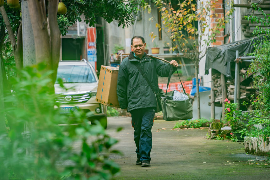 張林昌挑著包裹準備乘坐輪渡,前往河對岸村民組派送包裹。人民網 涂敏攝