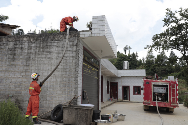 消防隊隊員正在為村民樓頂的儲水罐進水。