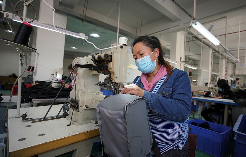 10月11日，工人在移民安置社區“幫扶車間”加工背包。