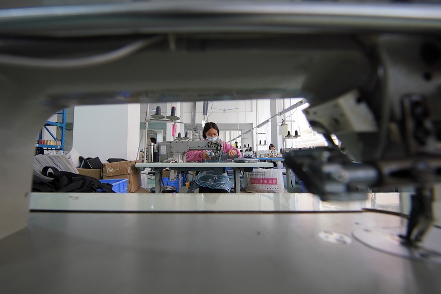 10月11日，工人在移民安置社區“幫扶車間”加工背包。