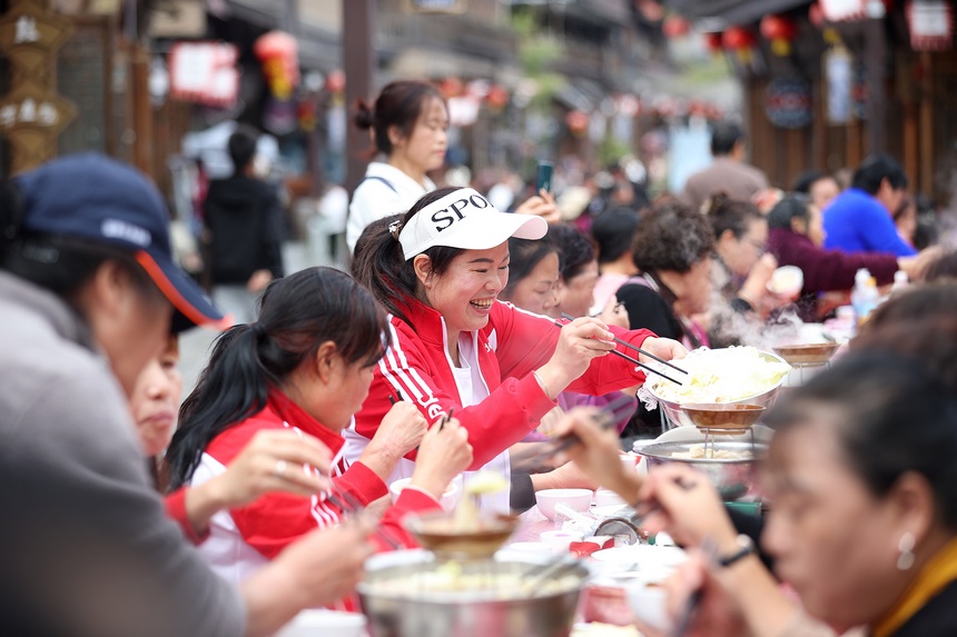 10月31日，游客在丹寨縣萬達小鎮長桌宴上品嘗當地美食。
