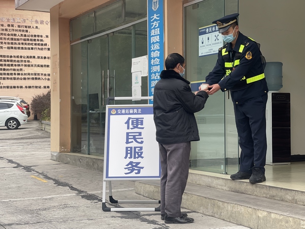 貴畢公路大方超限站執(zhí)法人員給過往貨車司機倒熱水。