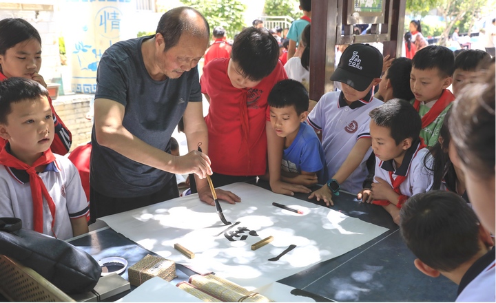 圖為黔西南州老年書畫研究會會員現場給同學們傳授講解書法。