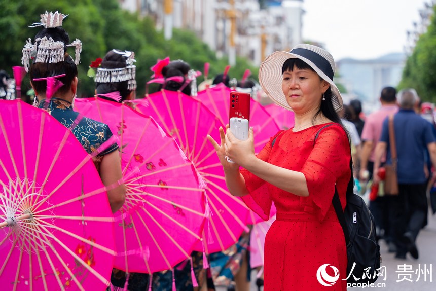 圍觀的群眾用手機拍攝少數民族同胞巡游。人民網記者 涂敏攝