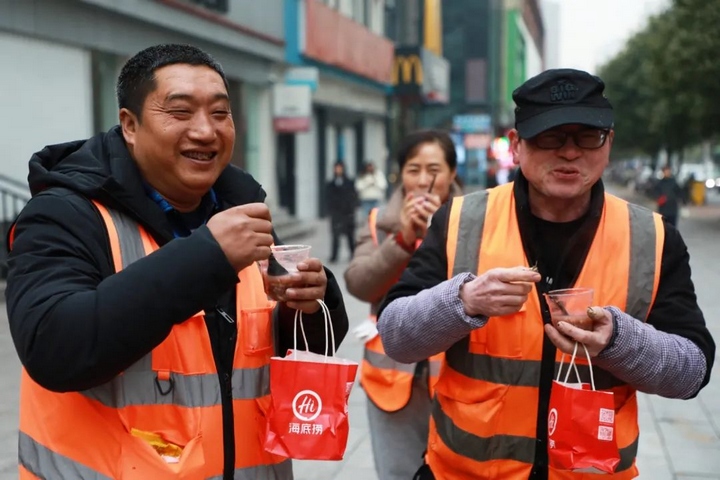 1、環衛工人們喝著愛心粥,臉上洋溢著暖心的笑容。