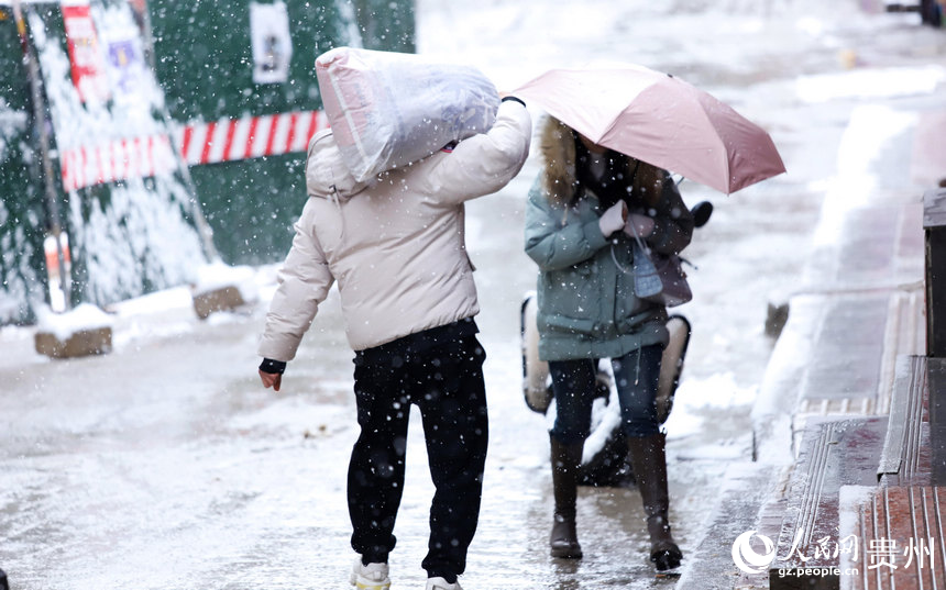 行人扛著袋子在雪中行走。人民網(wǎng) 顧蘭云攝