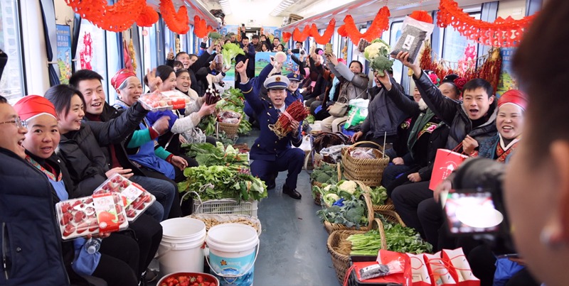 村民們舉著谷果蔬菜在“慢火車”上合影。實習生黃小桃 攝