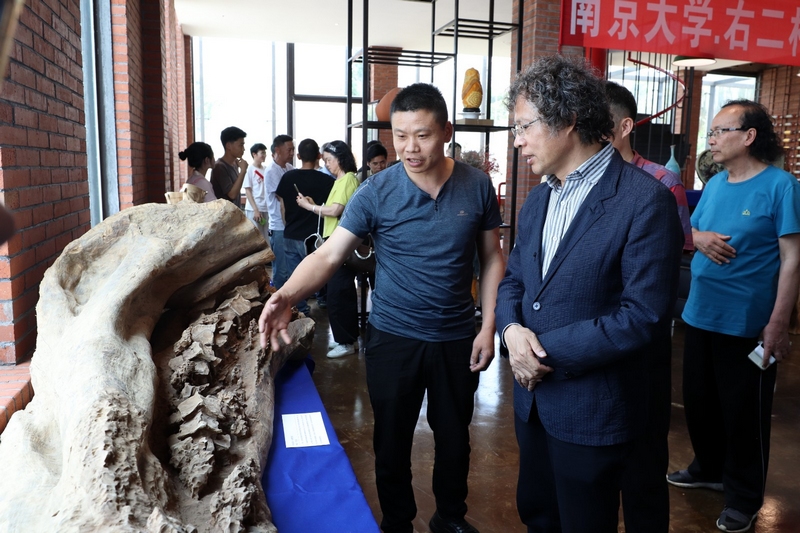 “兵工匠”劉吉武(左一)介紹其雕刻的工藝作品。