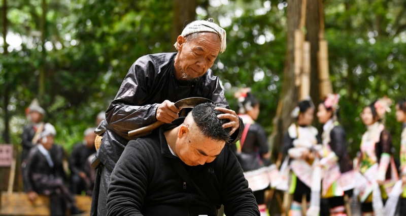 2024年5月1日，一名游客在貴州省黔從江縣丙妹鎮岜沙苗寨景區體驗鐮刀剃頭。