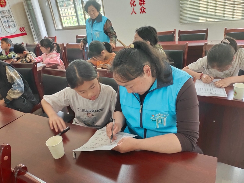 清鎮市大書法公益志愿服務隊在為農村孩子輔導。（饒敏 攝）