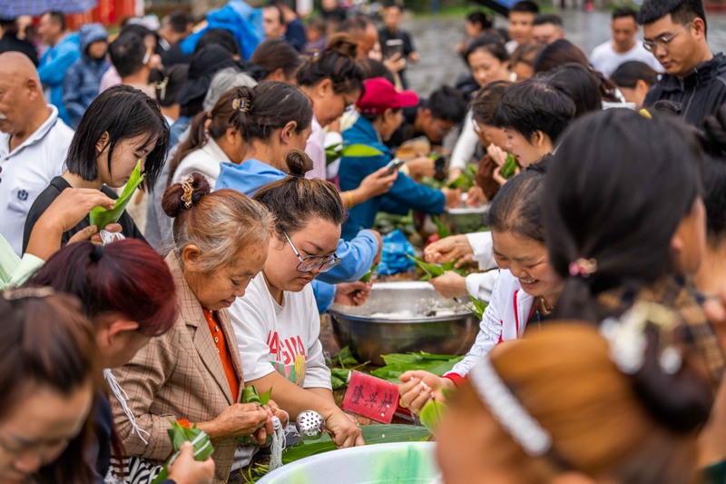 6月7日，游客在貴州省畢節(jié)市黔西新仁苗族鄉(xiāng)化屋村體驗包粽子。