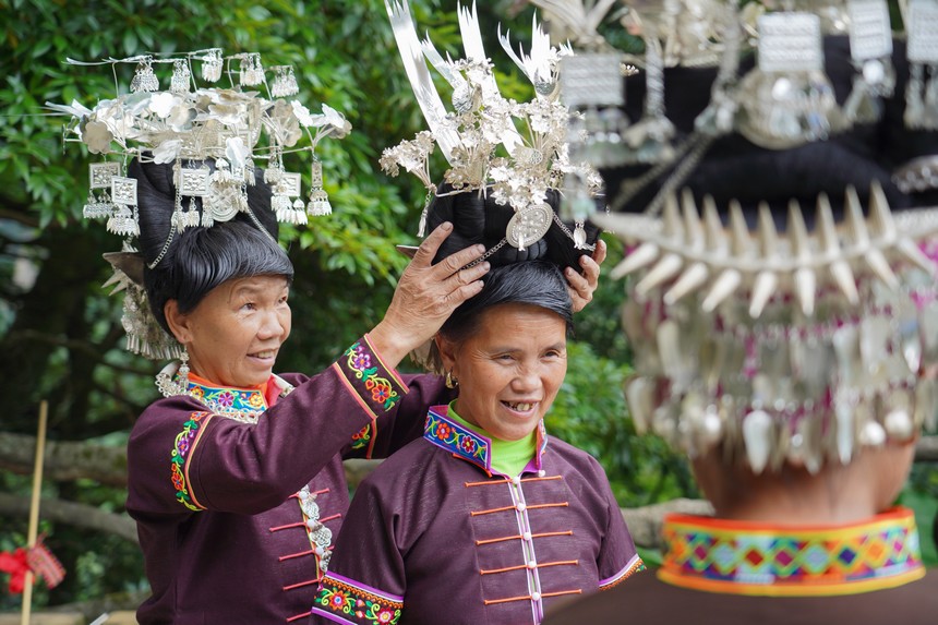 7月10日，貴州省丹寨縣排調(diào)鎮(zhèn)羊告村，李金英（左一）幫助苗族婦女戴銀飾。