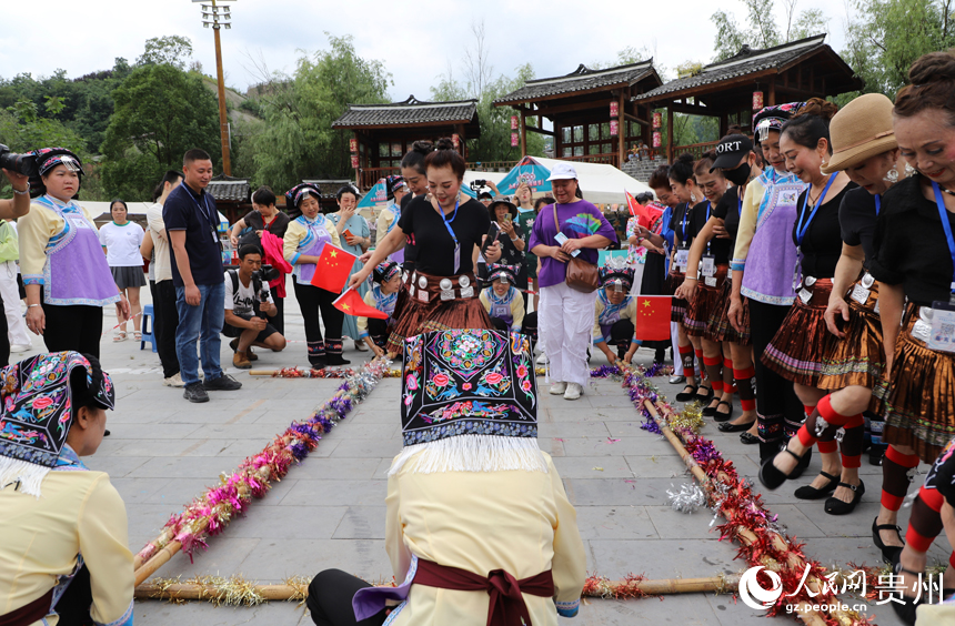 當地群眾邀請游客參與跳竹竿。人民網 龍章榆攝