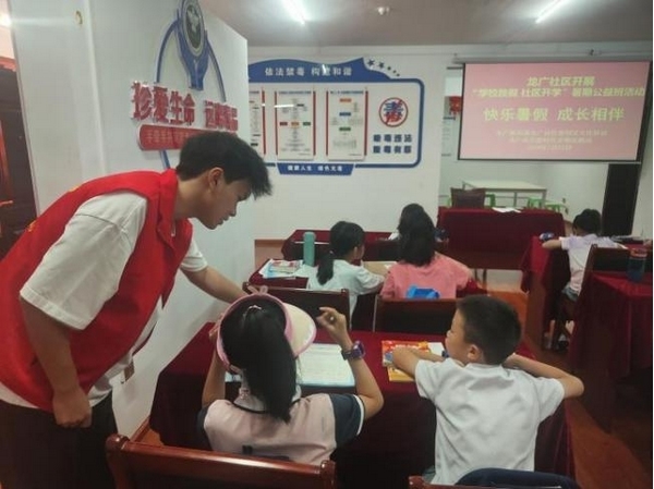 大學生志愿者正在輔導督促學生們做暑假作業。