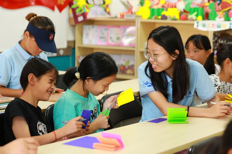 南昌大學的大學生志愿者指導孩子們做手工。