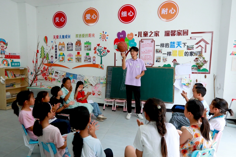 合肥工業大學社會實踐團的大學生志愿者和孩子們一起玩游戲。