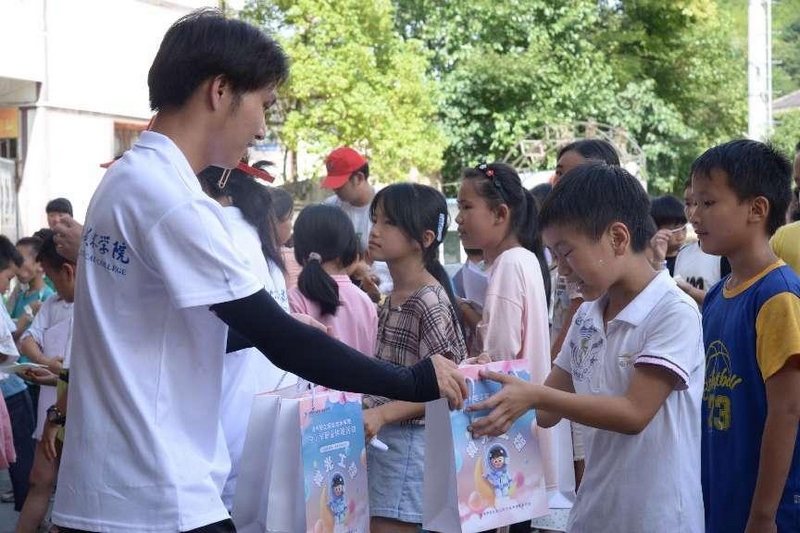 貴州輕工職業技術學院的志愿者給小朋友們發放禮物。