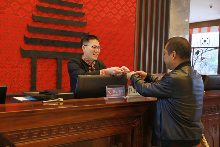 萬里將房卡遞給房客。楊潔茹攝