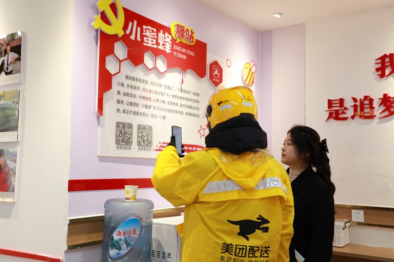 王涵(右)引導外賣小哥掃描流動黨員“歸隊碼”