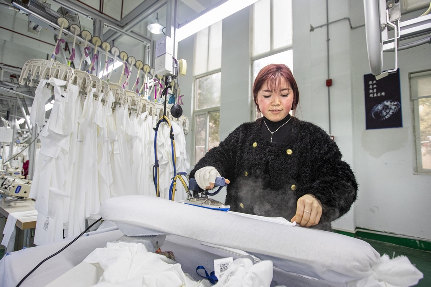 2025年2月5日，工人在貴州省畢節市黔西市經濟開發區一家服飾企業車間熨燙服飾。