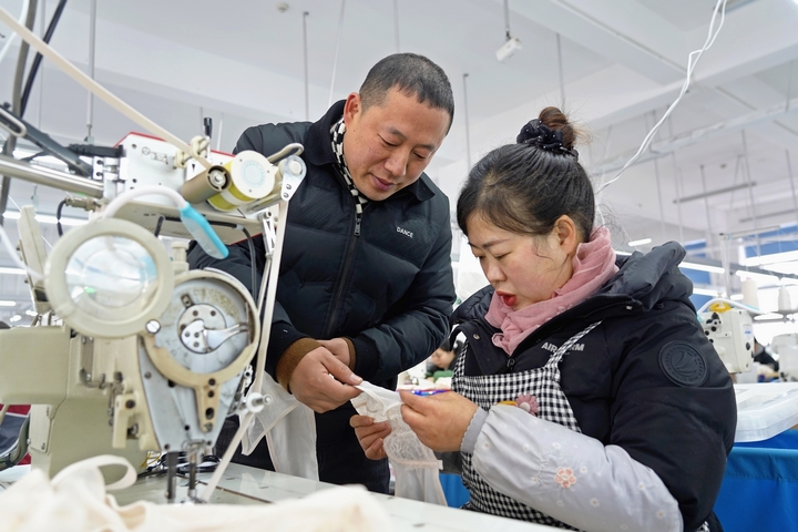 2025年2月25日,位于貴州省畢節市納雍縣工業園區的貴州博澤服裝有限公司生產車間,車間負責人與員工一起討論產品制作工藝。 楊英 攝.jpg