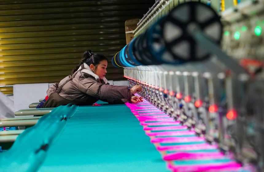 在貴州省從江縣美娥社區一家民族刺繡企業生產車間，工人在用數控機床生產刺繡產品。