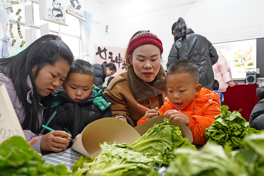 2025年3月6日，貴州省畢節市納雍縣龍場鎮中心幼兒園“溫情三八·感恩有您”活動現場，家長和孩子們一起做手工。 楊 英 攝