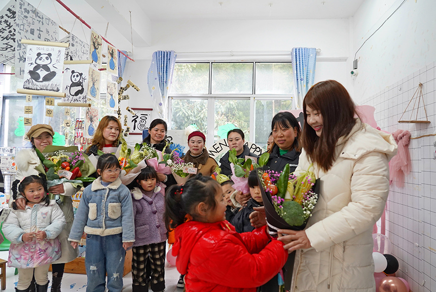 2025年3月6日,貴州省畢節市納雍縣龍場鎮中心幼兒園“溫情三八·感恩有您”活動現場,小朋友把親手制作的蔬菜花送給媽媽。 楊英 攝