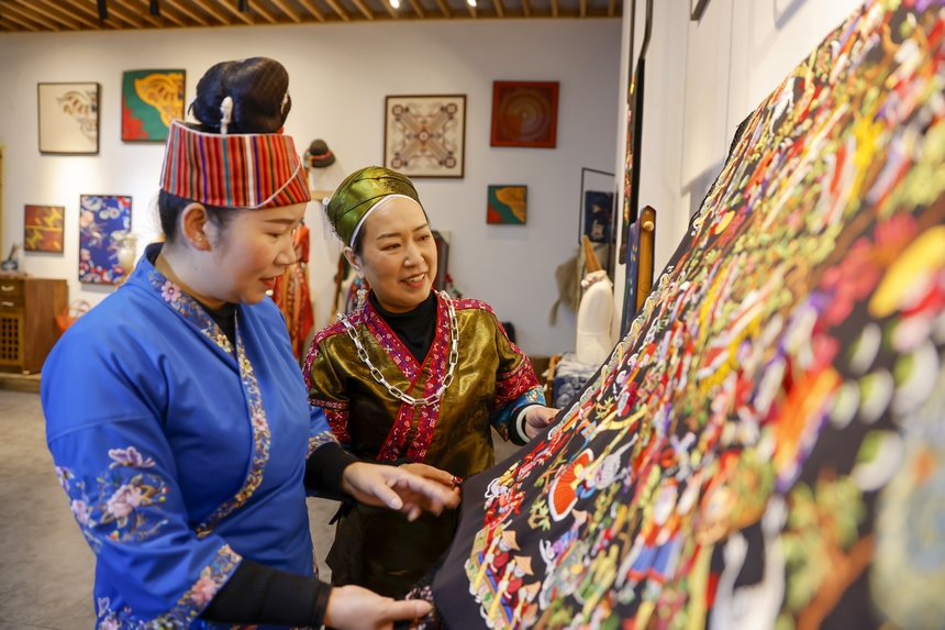 龍祿穎（右）與公司員工在交流苗繡技法。