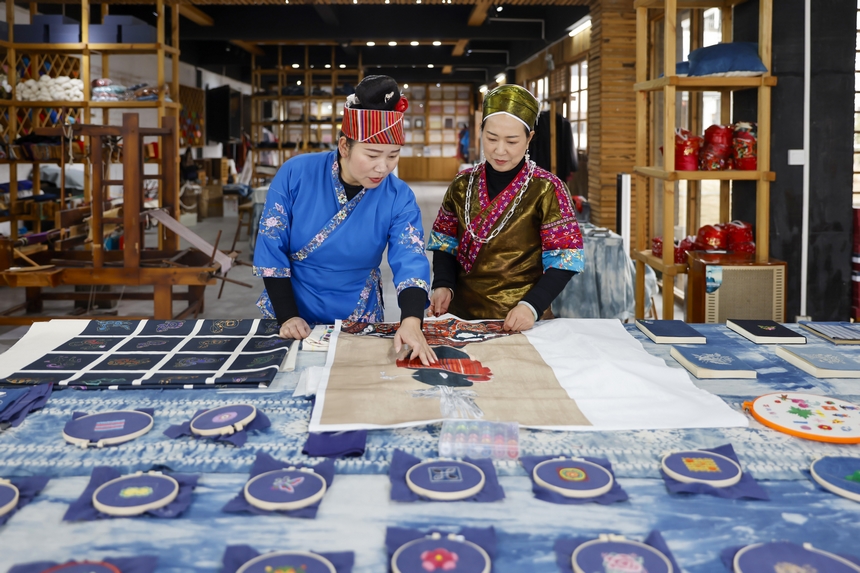 龍祿穎（右）與公司員工在手工刺繡車間交流苗繡新產品的設計理念。