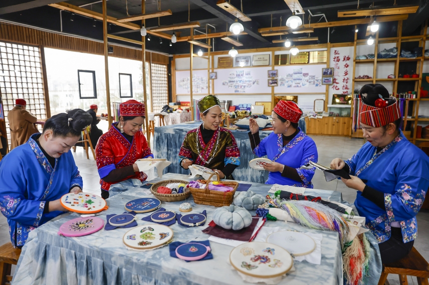 龍祿穎（中）與公司員工在手工刺繡車間刺繡。