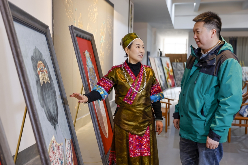 龍祿穎（左）在公司展廳向前來參觀的客人介紹苗繡產品。