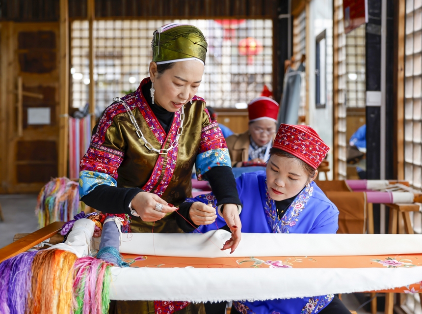 龍祿穎（左）在手工刺繡車間指導(dǎo)公司員工刺繡。