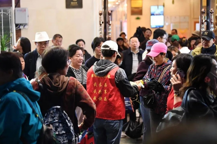 3 社區志愿者正在為出行的游客發放一次性雨衣.jpg