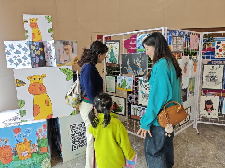 社區(qū)居民帶小朋友到活動現(xiàn)場觀看繪畫作品.jpg