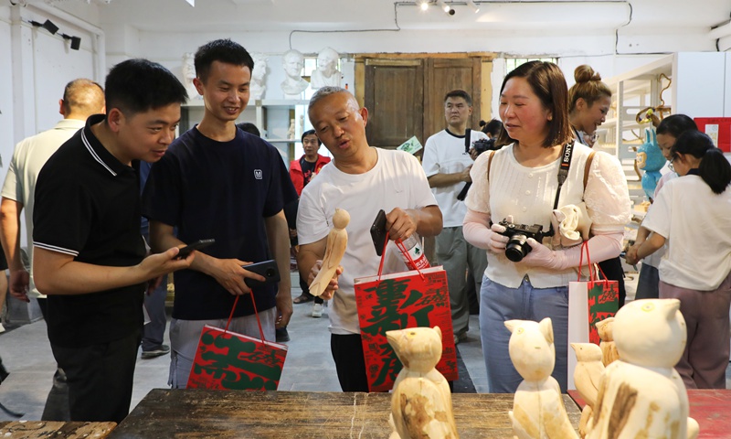 游客們駐足欣賞鄉(xiāng)土氣息濃郁的藝術(shù)作品。陳桂良攝