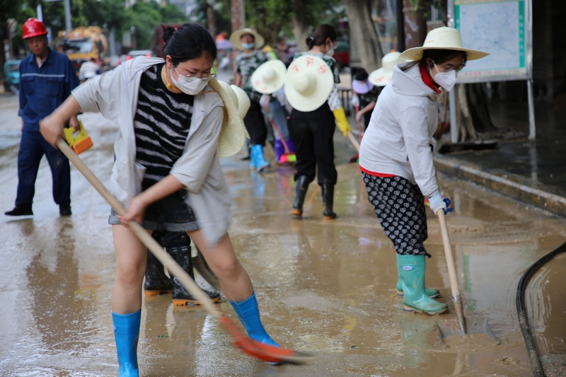 榕江縣稅務局第三黨支部書記蔣光慧在網格區域認真打掃淤泥。