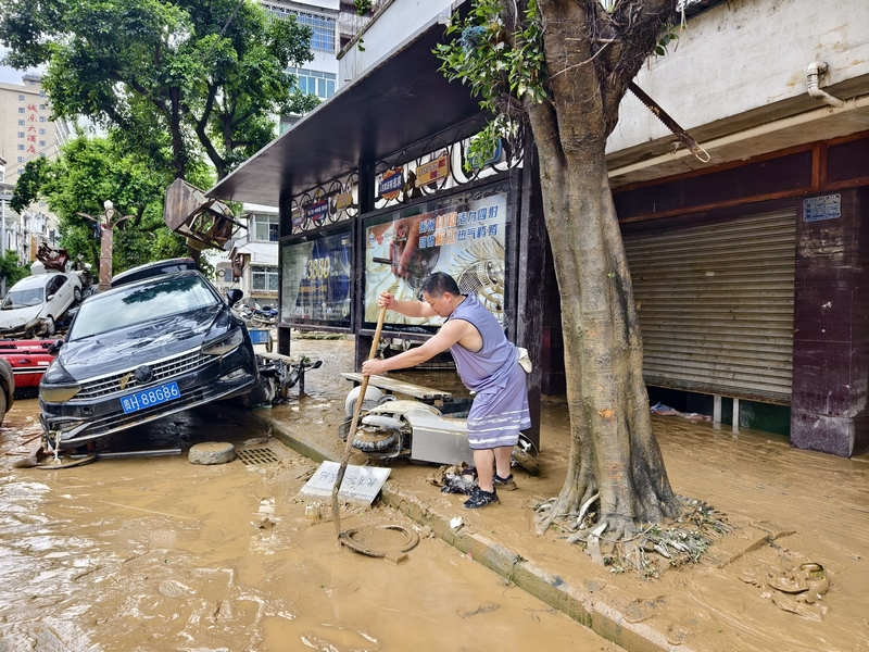 榕江縣稅務局黨委委員、副局長陳風在清掃縣城主大街淤泥。