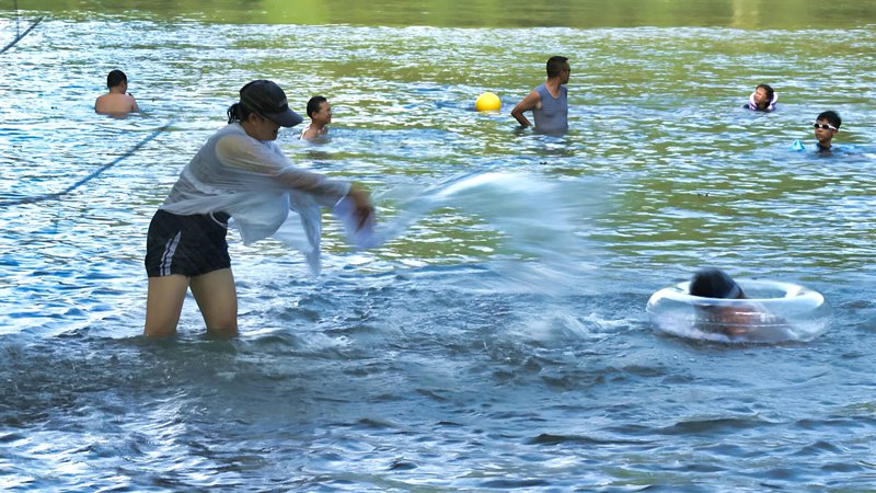 家長(zhǎng)和孩子在水中戲水。