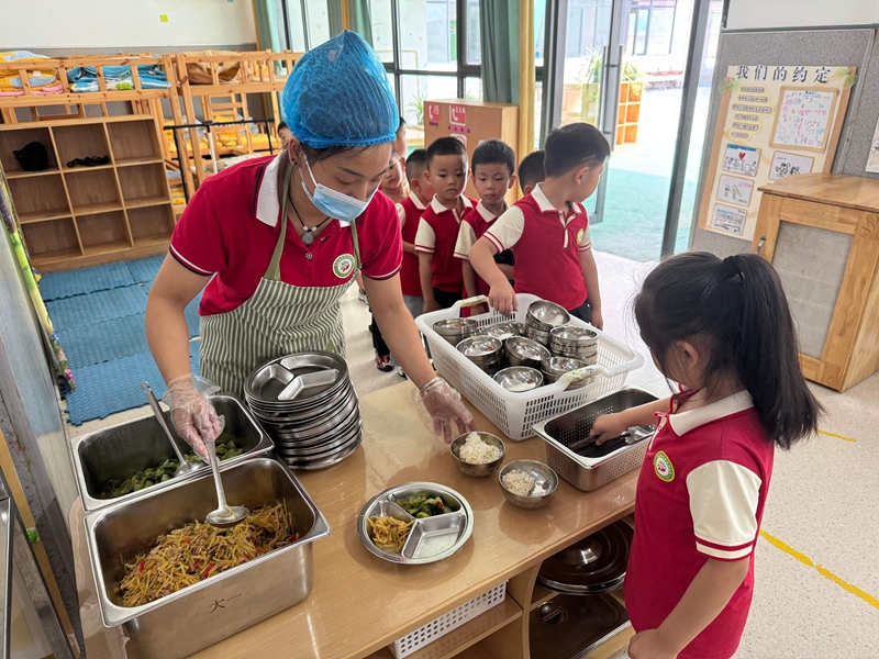 幼兒園工作人員為孩子們分餐，餐食豐富多樣。謝永恒  攝.jpg