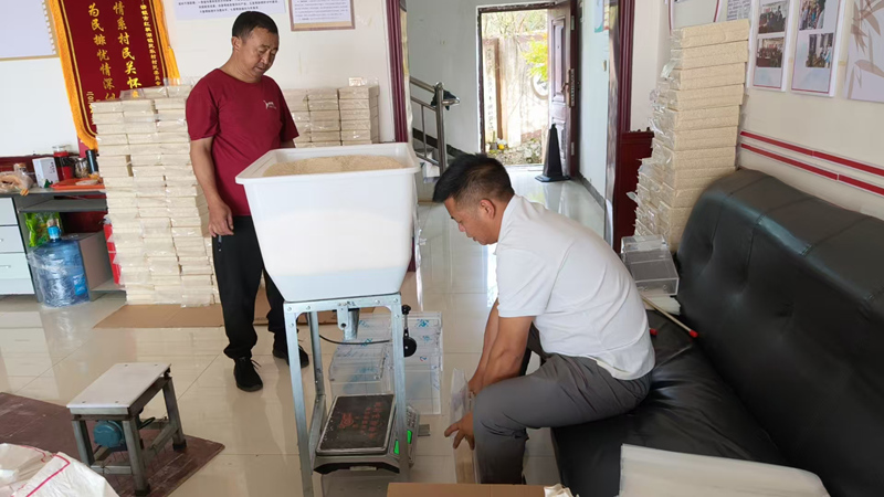 工作人員幫助村民真空包裝大米。