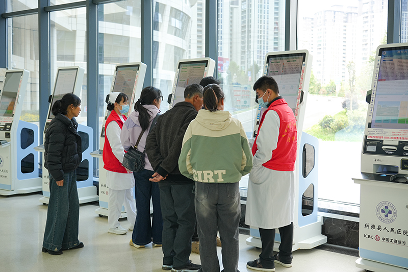 導(dǎo)診護(hù)士指導(dǎo)群眾操作自助掛號(hào)機(jī)掛號(hào)就診。胡璐攝