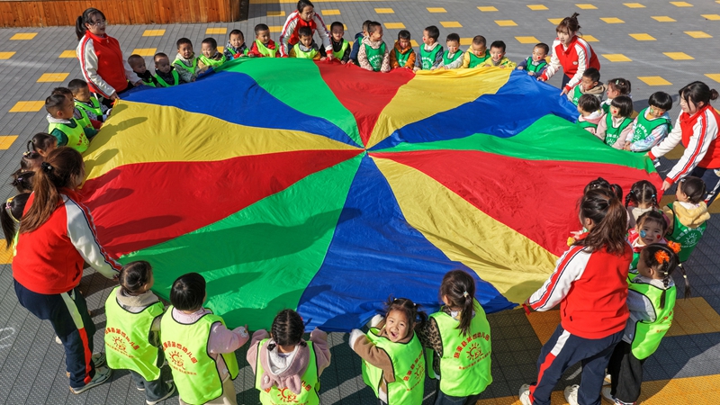 2025年11月27日，貴州省黔東南苗族侗族自治州施秉縣第四幼兒園的小朋友在參加彩虹傘趣味游戲活動。