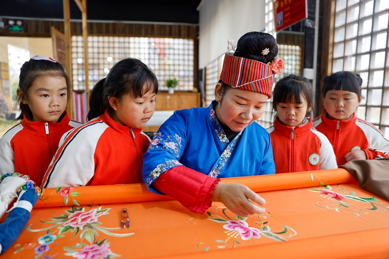 2025年12月10日，非遺代表性傳承人在給貴州省黔東南苗族侗族自治州施秉縣第四幼兒園的孩子們展示苗繡技藝。