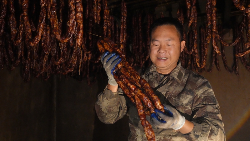 楊天才展示烤房里的香腸。彭開燚 攝.JPG