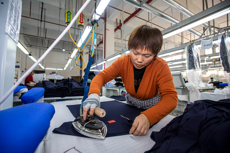 工人在貴州省畢節(jié)市黔西市經(jīng)濟(jì)開發(fā)區(qū)一家服飾企業(yè)車間生產(chǎn)線上熨燙服飾。