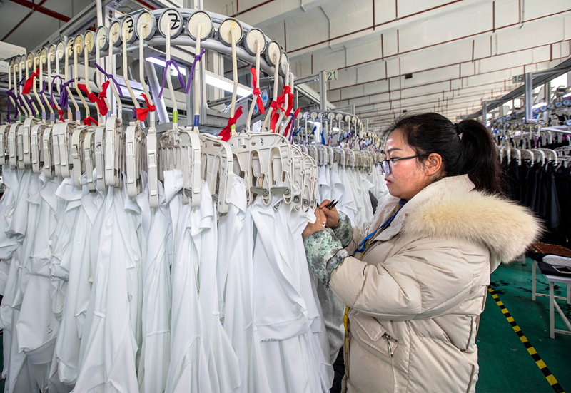 工人在貴州省畢節市黔西市經濟開發區一家服飾企業車間生產線上加工服飾。