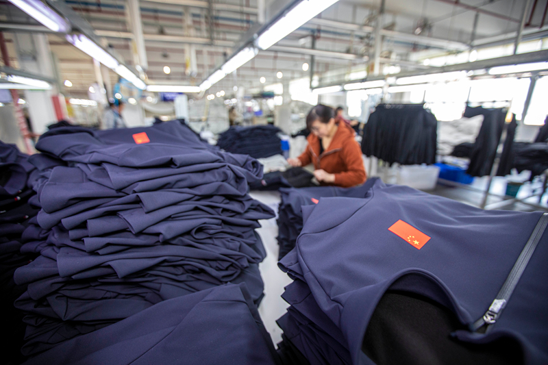 工人在貴州省畢節市黔西市經濟開發區一家服飾企業車間生產線上整理服飾。