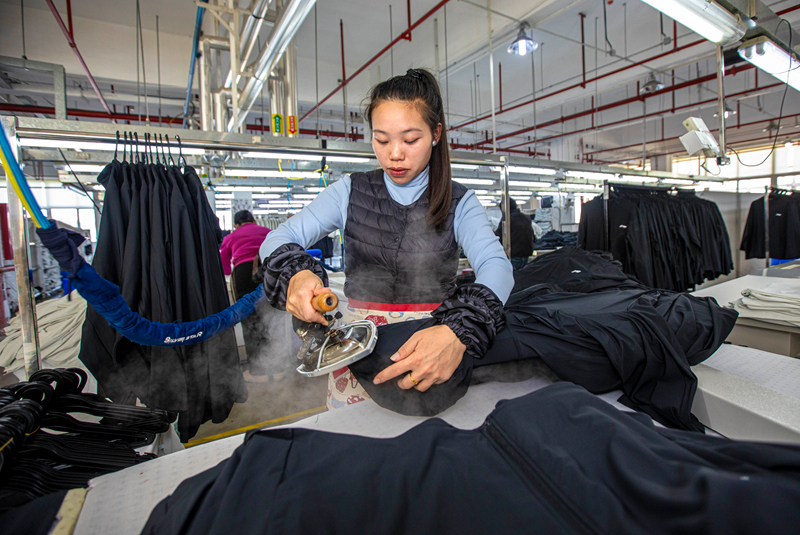 工人在貴州省畢節(jié)市黔西市經(jīng)濟(jì)開發(fā)區(qū)一家服飾企業(yè)車間生產(chǎn)線上熨燙服飾。